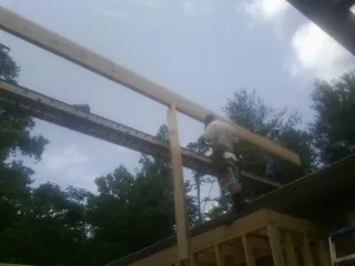 Carpenter setting a ridge beam over a new addition frame — Ice Dam Removal by Roofing Brothers in Cross City