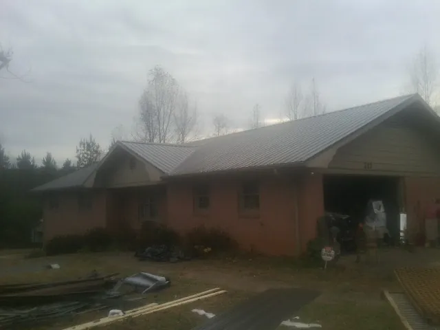 Gray metal roof on a stucco house with an attached garage in Cross City