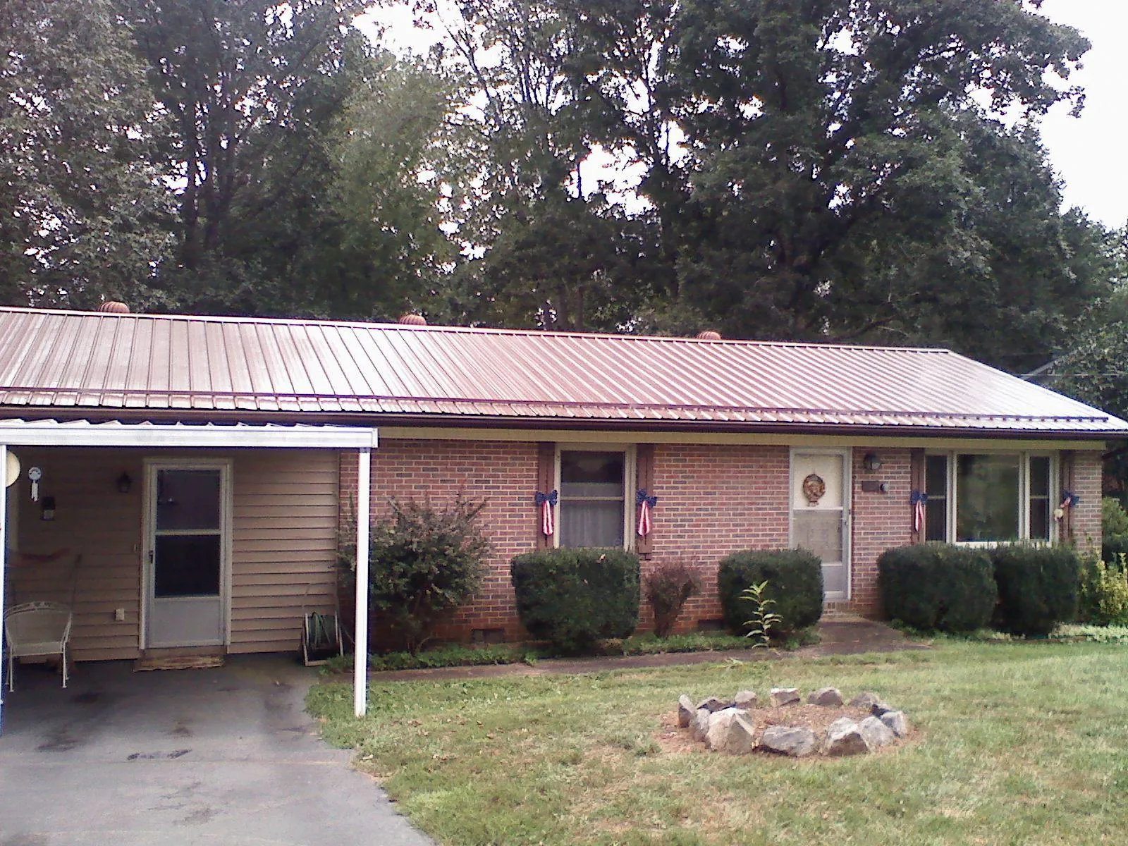 Bronze metal roof and carport on a brick ranch home — Roof Repair work by our crew in Cross City