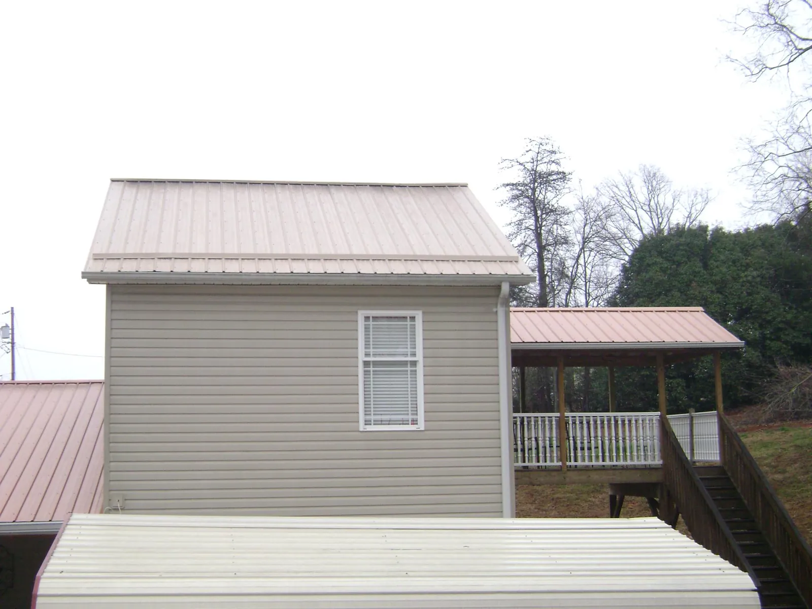 Tan metal roofs on a two story addition and attached porch, from a Roof Replacement job in Cross City