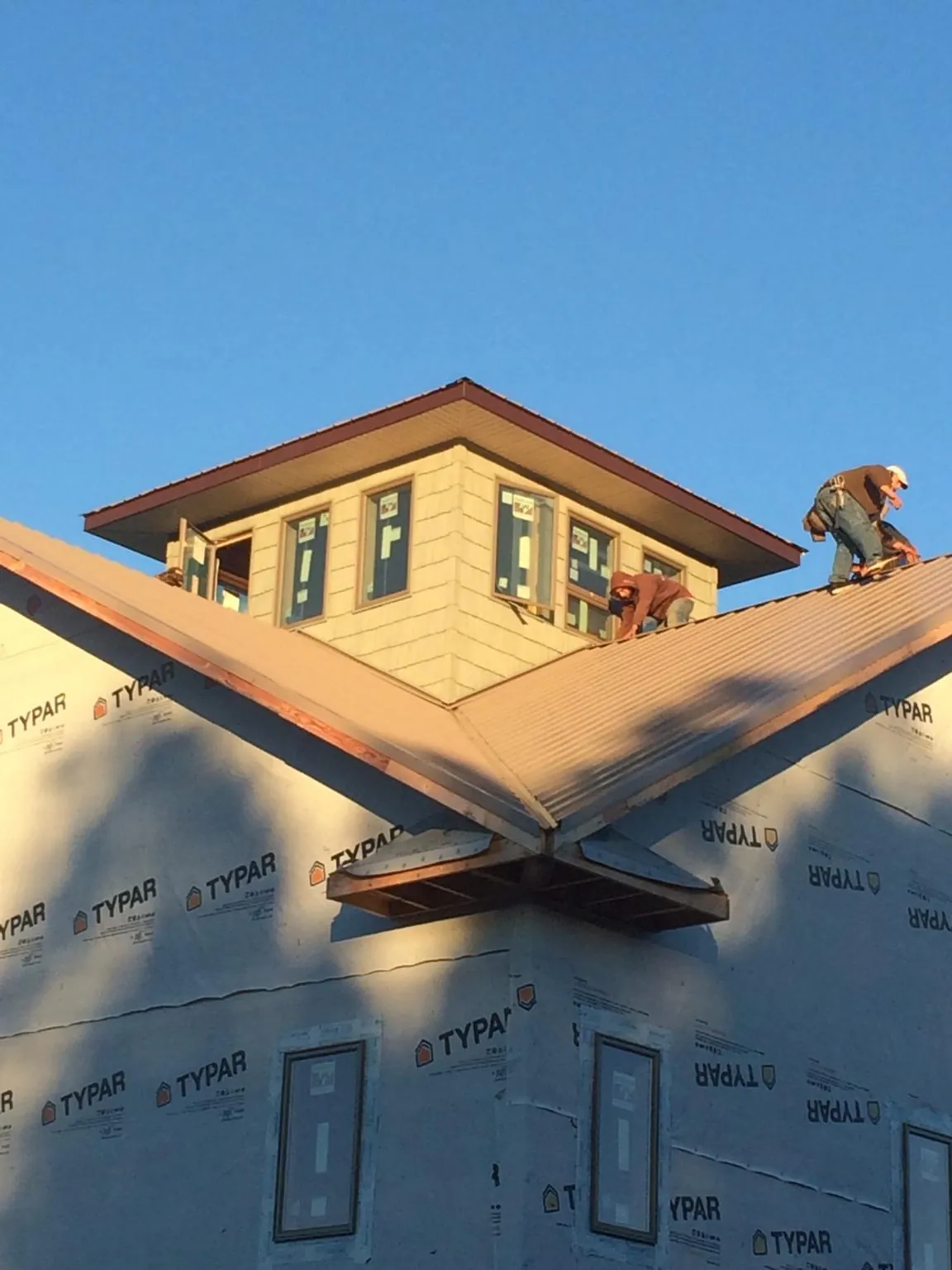Roofers working around a rooftop cupola on a new metal roof at sunset — Roof Waterproofing in Cross City by Roofing Brothers